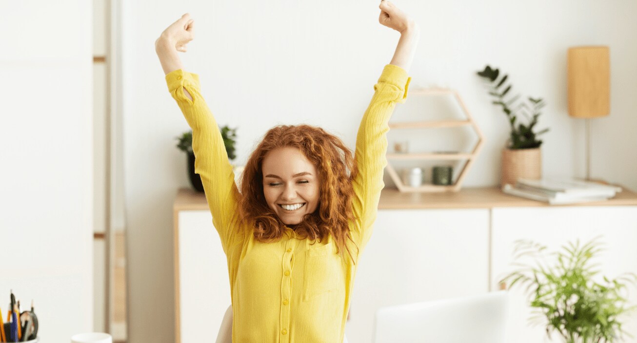 Woman in yellow sweater stretching while working from home