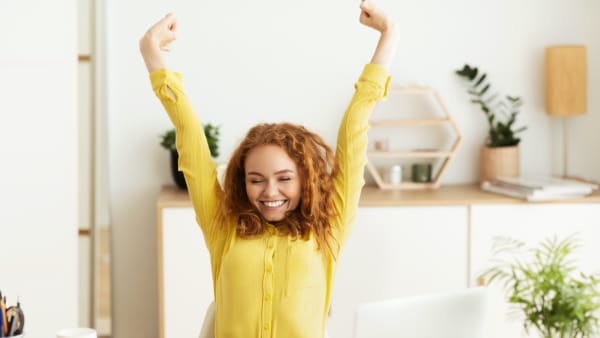 Woman in yellow sweater stretching while working from home