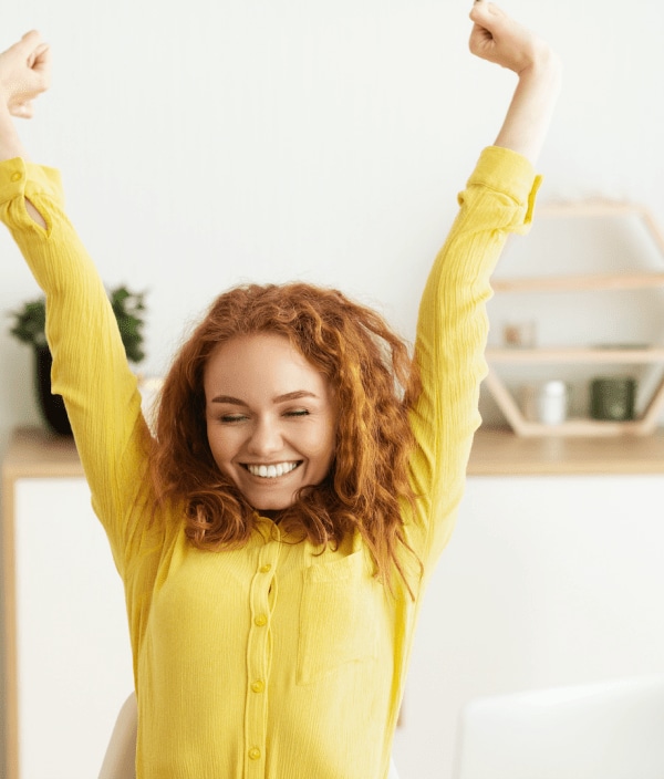 Woman in yellow sweater stretching while working from home
