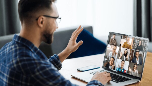 Man waving at a computer while on a video conference call