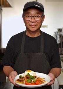 Chef holding a plate of food at one of Eric Ong's restaurants