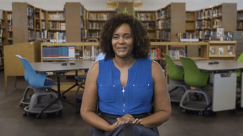 Educator is interviewed in a high school library.