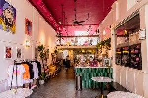 Colorful coffee shop with a pink ceiling, lofted seating area and green counter.