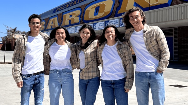 Five high schoolers of various ethnicities pose in tan flannels and white t-shirts.