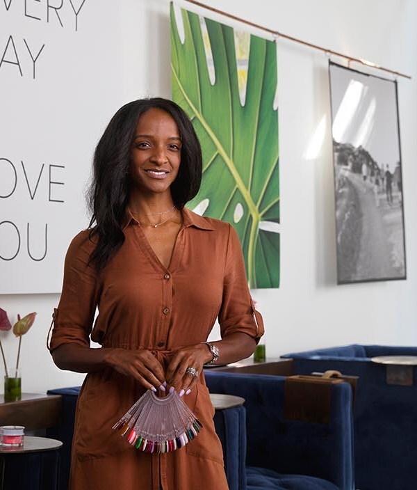 A Black, female business owner poses in her luxury nail salon.