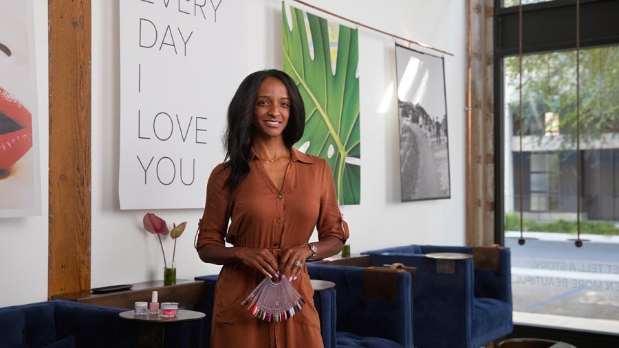 A Black, female business owner poses in her luxury nail salon.