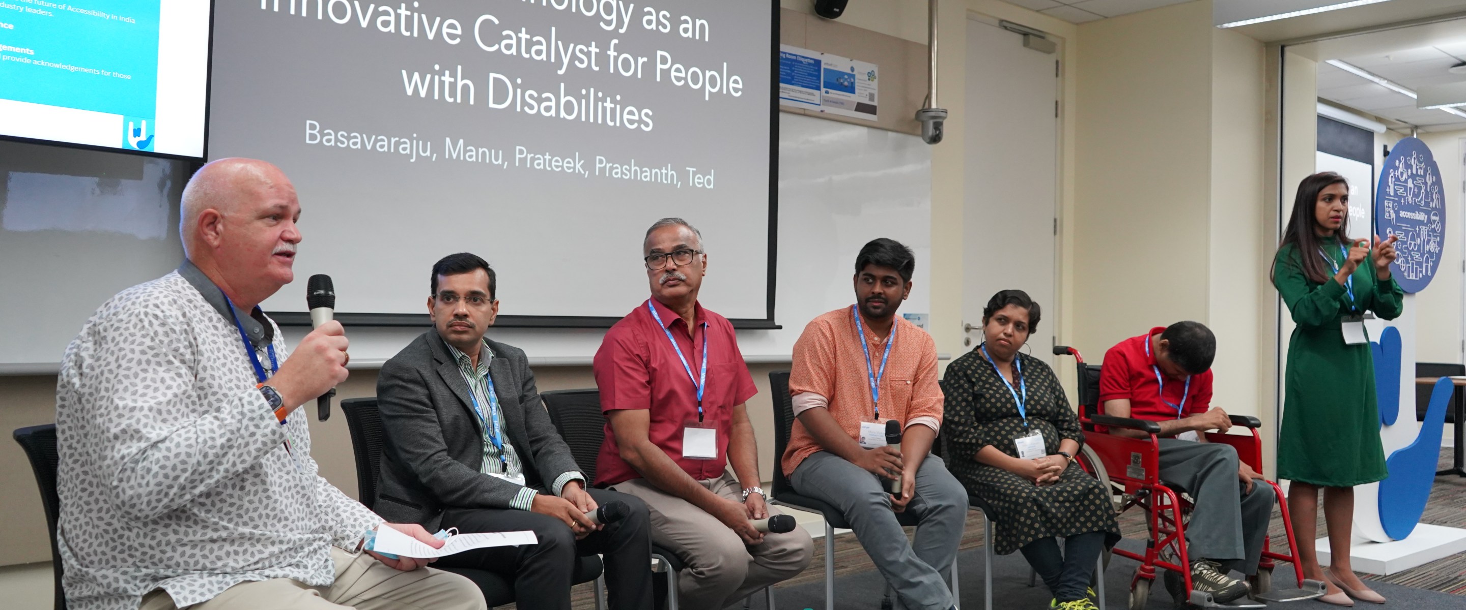 A diverse group of people on stage with a background reading, "Technology as an innovative catalyst for people with disabilities.: