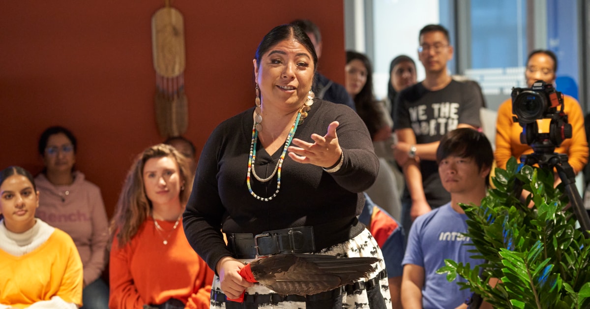 An Indigenous woman performs a blessing ceremony to employees in an office.