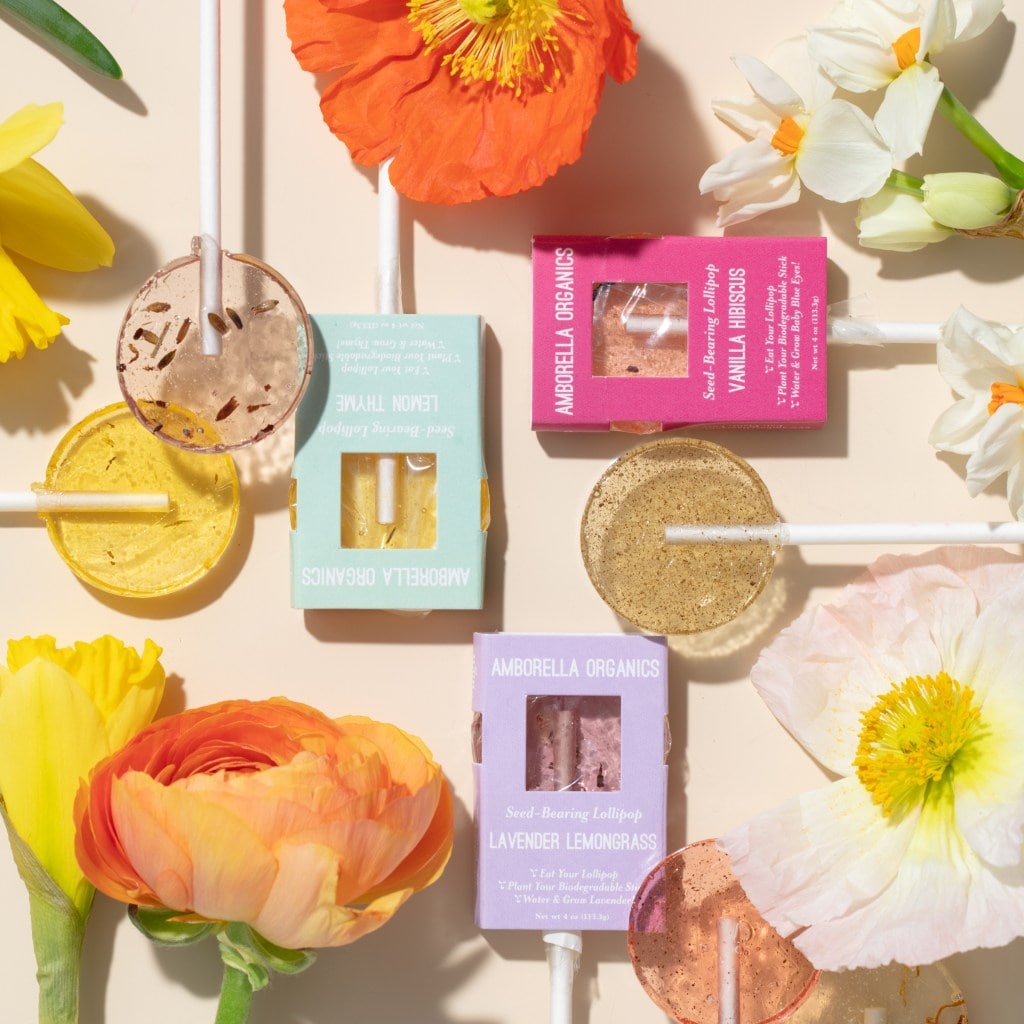 Lollipops in bright packaging with flowers around them.