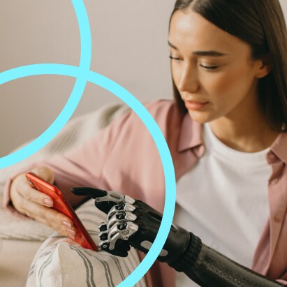 A young woman with brown hair uses her smartphone with a robotic prosthetic hand.