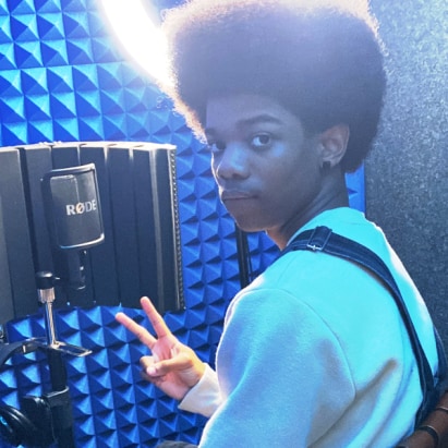 Boy in soundbooth with blue light and recording equipment