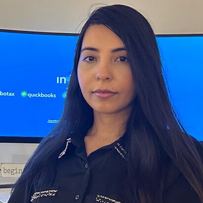 Brunette woman sitting in front on computer monitor that had Intuit logo.