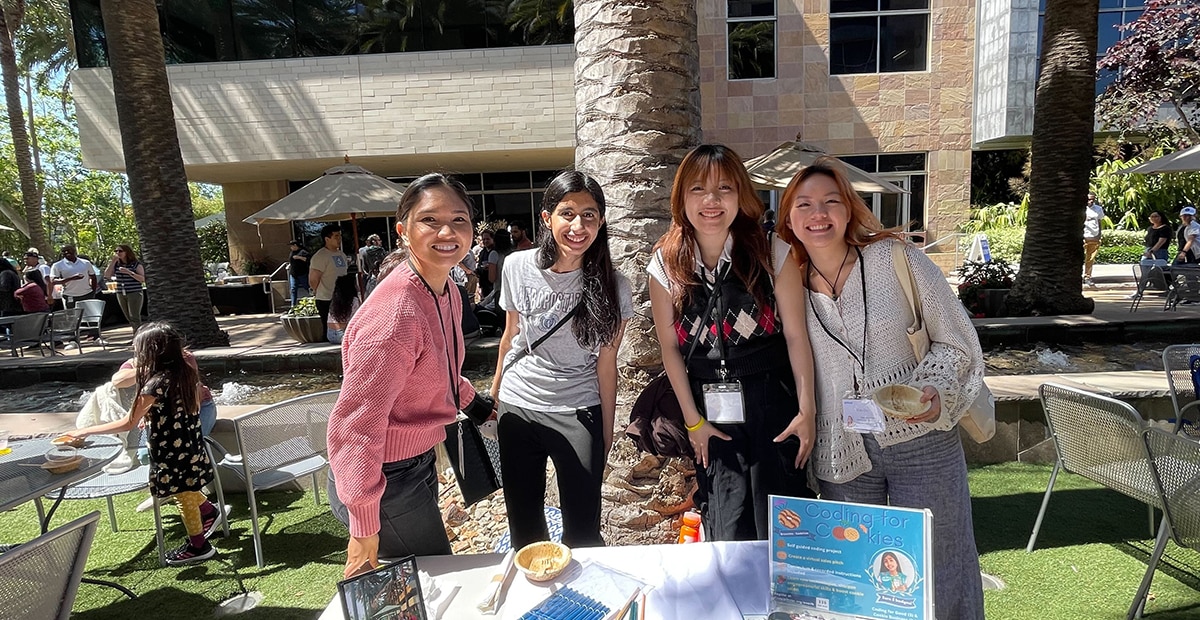 Four women standing behind 'Coding for Kids' booth