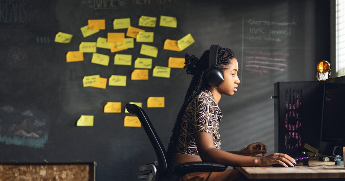 Woman working in front of her desk, behind her a collage of sticky notes