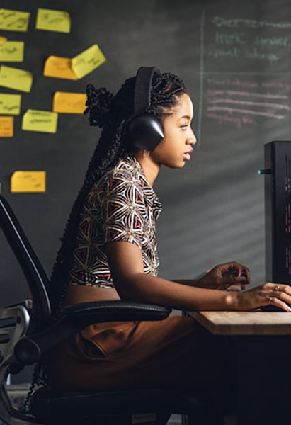 Woman working in front of her desk, behind her a collage of sticky notes