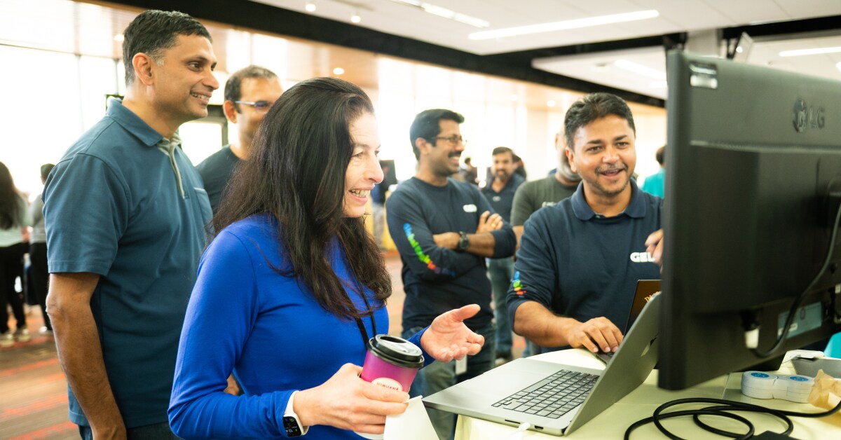 Various happy individuals gathered around a computer screen.