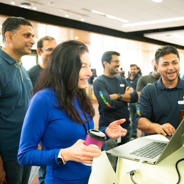 Various happy individuals gathered around a computer screen.