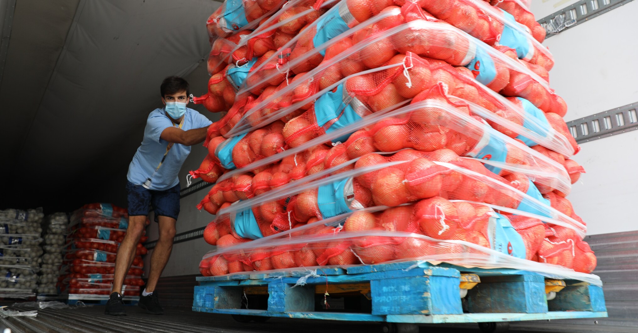 Man with mask pushing cartons of food out of a truck