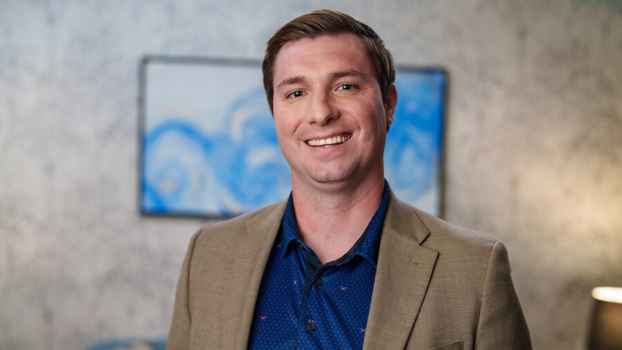 A smiling person in a blue shirt and striped tie.