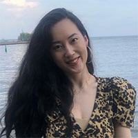 Photo of a smiling woman standing in front of a body of water