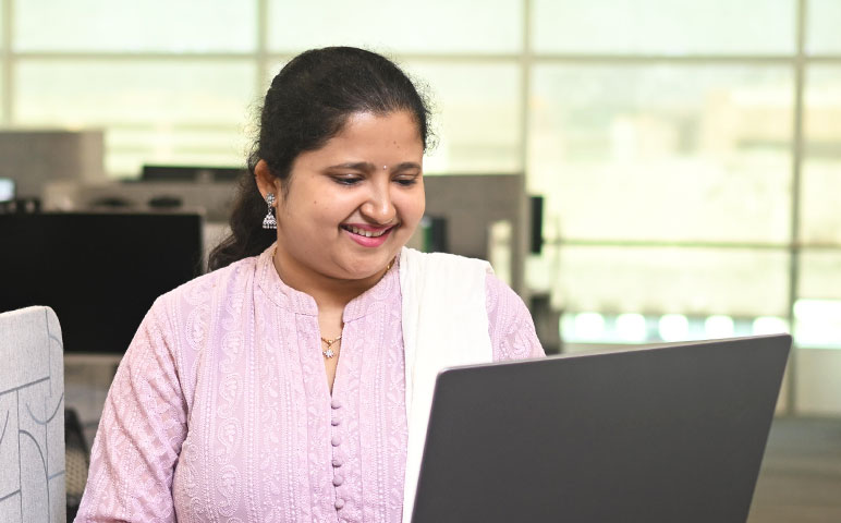 A person smiling while looking at a laptop.