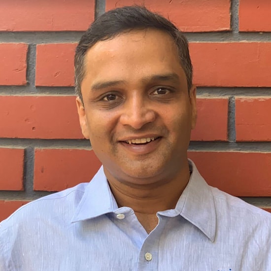 A person smiling and wearing a shirt and tie.