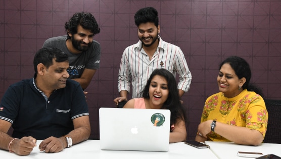 Employees huddling over laptop