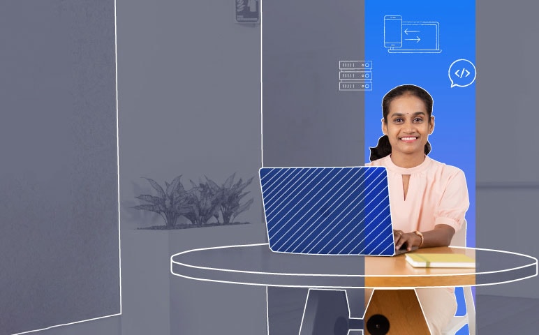 A person sitting at a desk with a laptop and a desktop computer.