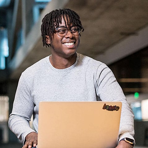 A person with glasses smiling in front of his computer