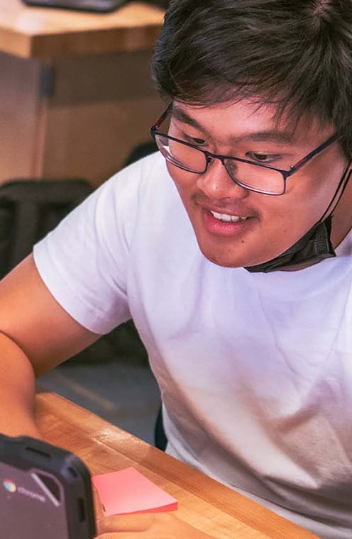 A student wearing glasses working from his computer