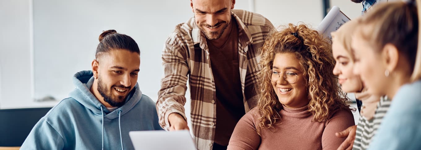 Happy college students and their teacher using computer in classroom