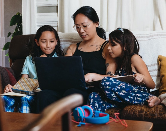 A mom and her kids reading from their laptop