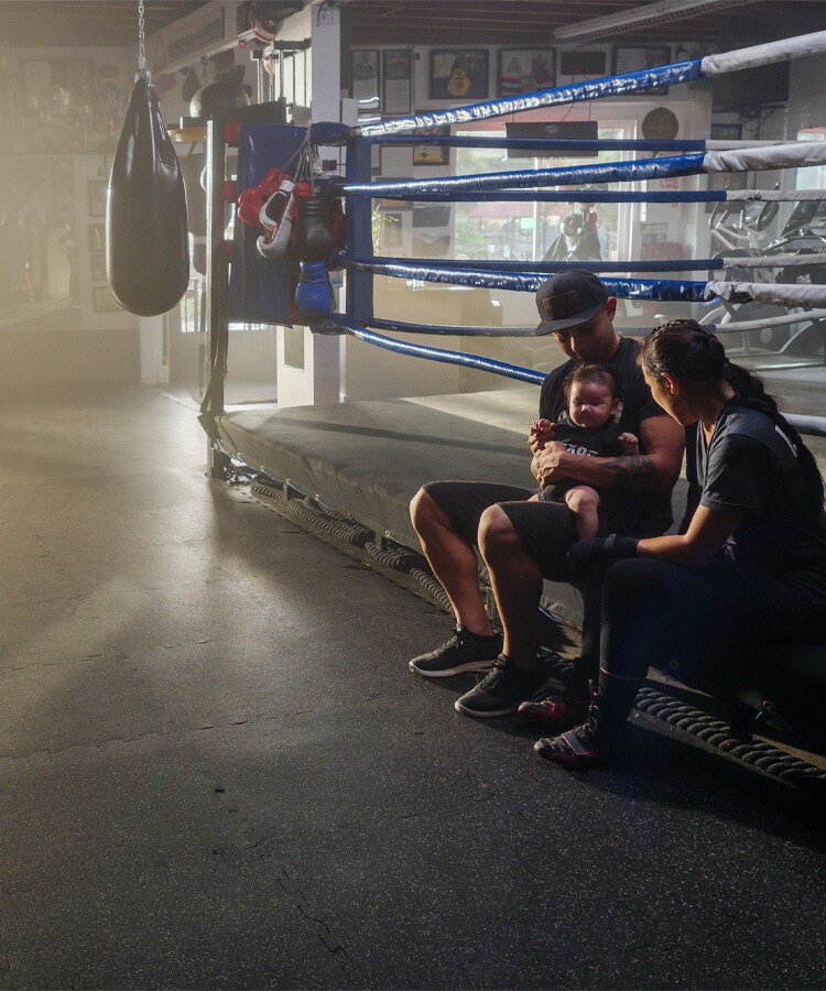 Husband and Wife holding baby sitting on a boxing ring