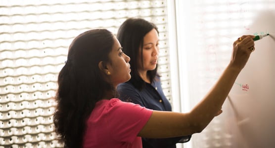 Two women drawing on the white board