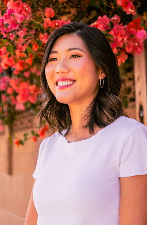 A person smiling with flowers in the background