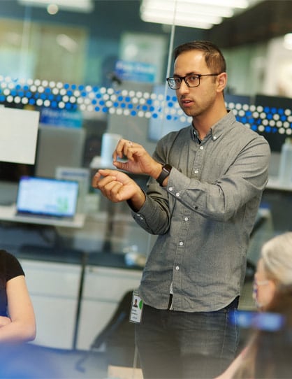 data-science-employee-presenting-photo-icom-desktop-418x542.jpeg A person and person standing in front of a computer.