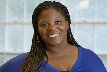 A person smiling and wearing a blue shirt and a neck tie.