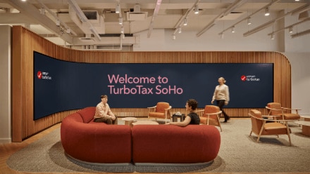 Three people sitting at a table with a large picture of a baby.