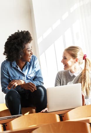 Two people sitting on a couch with a laptop.