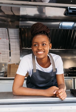 A person smiling while standing in a kitchen.