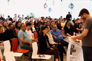 A group of people sitting in a room with a speaker.