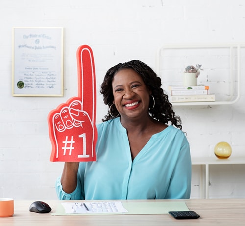 Intuit Expert - Sitting at her desk and holding a #1 sign 