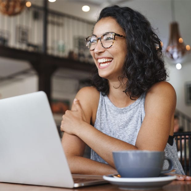 Female student using laptop sitting at a cafe