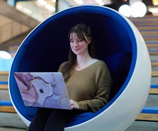 A person is sitting in a chair with a computer.