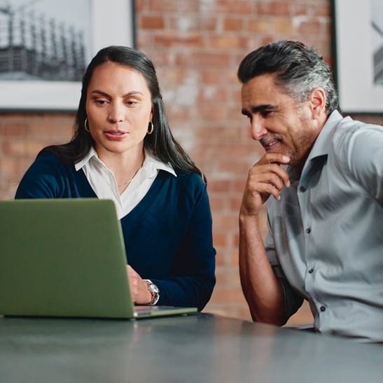 Two people sitting around a table looking at a laptop