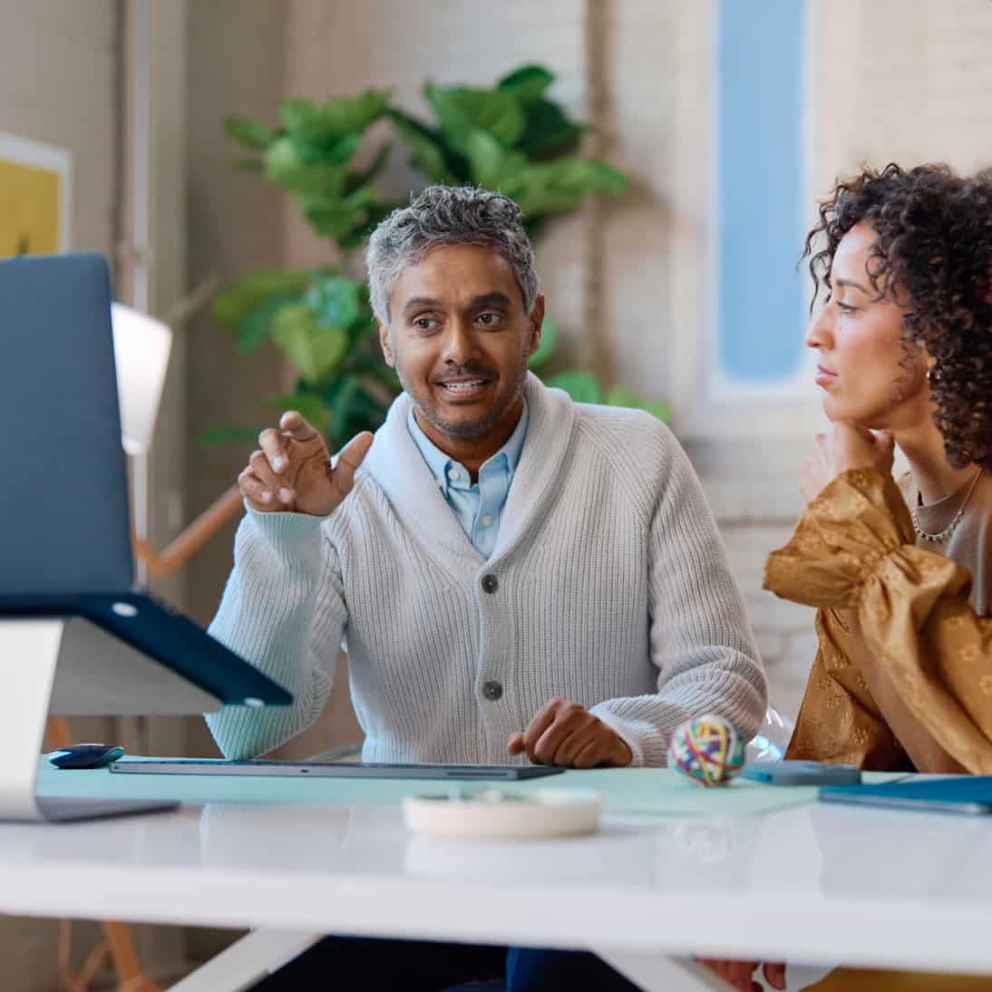 Two people sitting at a table looking at a laptop
