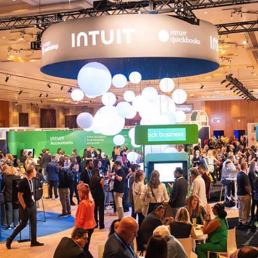 A crowd of people standing around a room filled with laptops.
