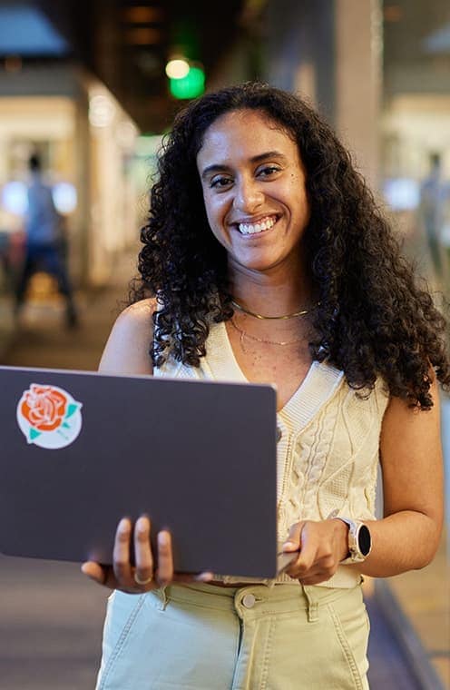 A person smiling and holding a laptop computer.