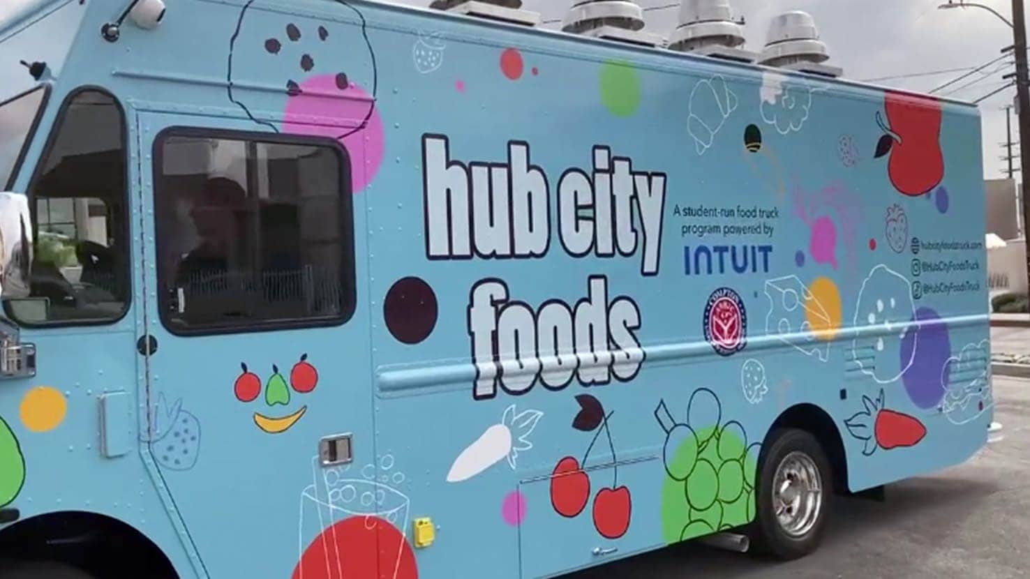 intuit-hubcity-foodtruck-photo-icom-desktop-738x415.jpg A blue bus with a drawing of a dog on the side.