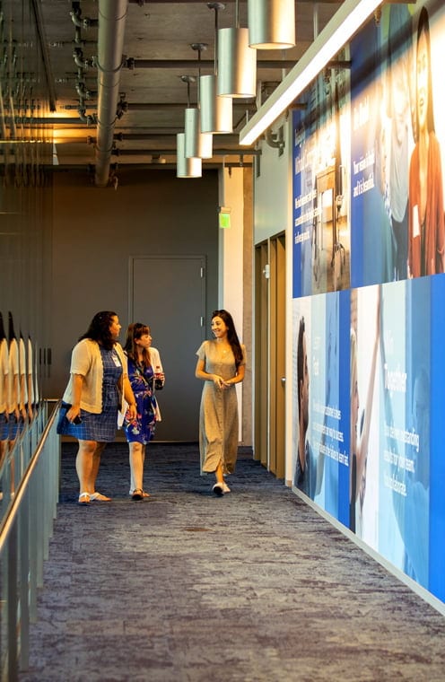 Intuit Press Room Three people are walking together in a hallway.
